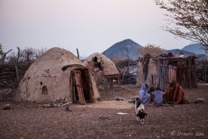 Himba people gathered in their blankets front of a traditional hut, Otjomazeva Village Namibia