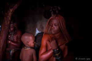 Himba woman in a dark hut Applying Ochre Paste, Otjomazeva Village, Kunene Namibia