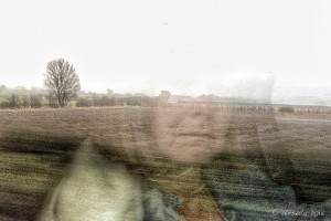 Woman's face reflected in a train window against a English winter landscape.