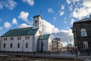 Street view of Reykjavík Cathedral against a blue sky.