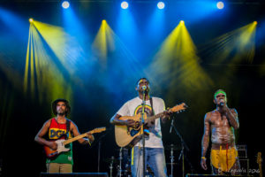 Indigenous band members from East Journey under blue and yellow Lights, Byron Bay Bluesfest 2016