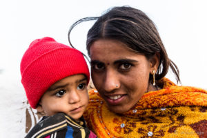 Rajasthani woman with a child in red hat, Khiyasariya village, India