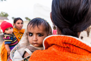 Kohl-Eyed Rajasthani Infant looking over his mother's shoulder, Khiyasariya village, India