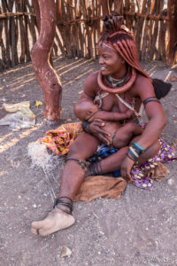 Young Himba woman nursing a baby, Otjomazeva Village, Kunene Namibia