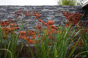 Grey stone wall with terracotta mural of Vietnamese farmers, Naman Retreat, Đà Nẵng
