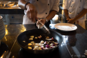 Man in white uniform with a heavy frypan, Hay Hay Restaurant Display Kitchen, Naman Retreat Danang Vietnam