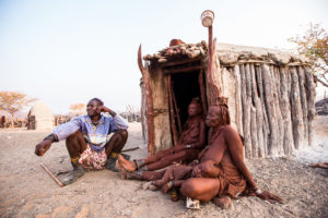 Three Himba sitting outside a hut, Kunene Region Namibia
