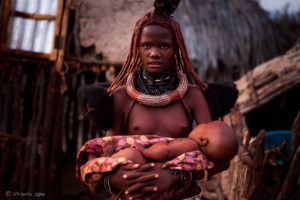 Young Himba woman with a bay i n a blanket, Kunene Region Namibia