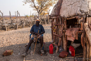 Smiling Himba man in the shade of a hut, Kunene Namibia