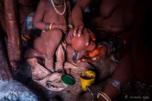 Himba woman pouring ochre powder into her hands, Kunene Region Namibia