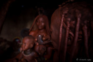 Old Himba woman with a pipe in a dark hut, Kunene Region, Nambia