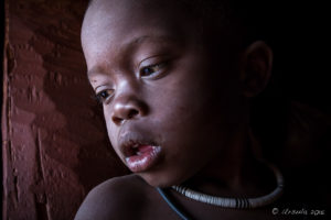 Young Himba Boy in a dark hut doorway, Kunene Region Namibia