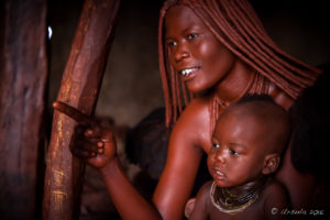 Himba woman and child in a dark hut, Kunene Region,