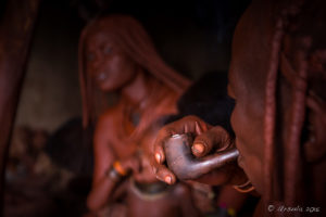 Old Himba woman with a pipe in a dark hut, Kunene Region, Nambia