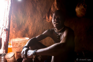 Young Himba man inside a dark hut, Kunene Region, Namibia