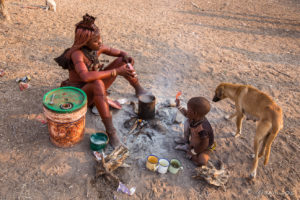 A Himba woman sitting on the ground making tea, Kunene Region, Namibia