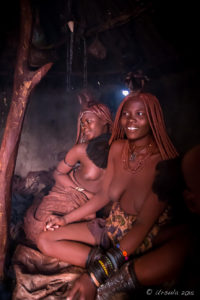 Young Himba women inside a dark hut, Kunene Region, Namibia