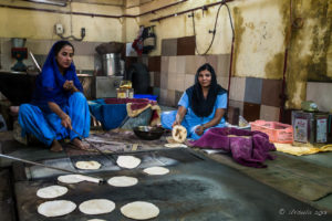 Sikh women cooking chapati on a large griddle, Gurudwara Sis Ganj Sahib, Chandni Chowk, Old Delhi