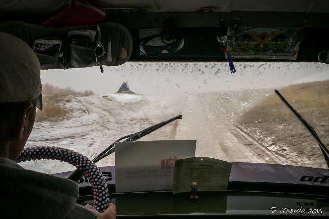 View from a UAZ windscreen over a snowy dirt road in Western Mongolia.