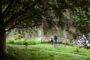 A couple on a rail over the Wye River, The Weir riverside garden, Herefordshire, UK