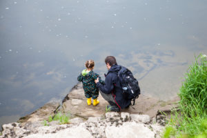 Man and child at the Wye River's edge, The Weir riverside garden, Herefordshire, UK