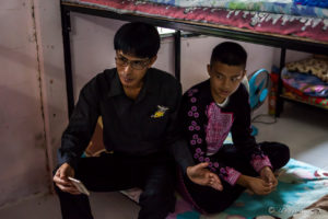 Thai teacher and Hmong boy in traditional costume on a Dormitory bunkbed, Santisuk School, Chiang Mai Thailand