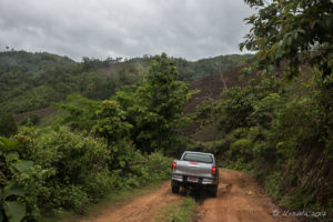 Utility truck on a rutted red-dirt mountain road, Mae Sariang Thailand