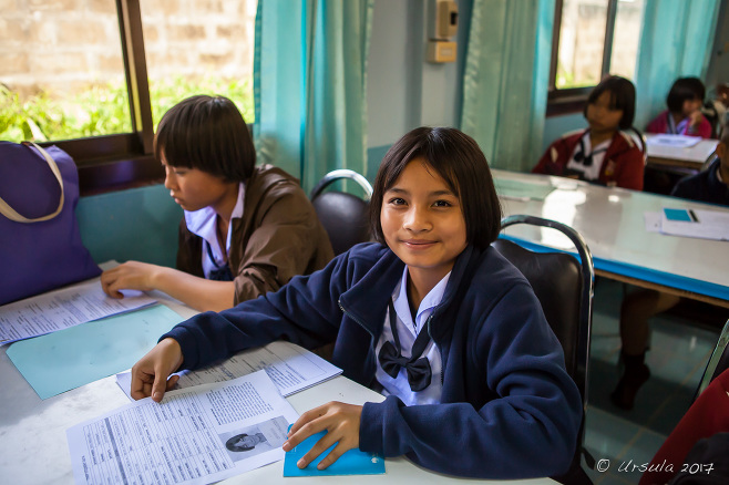 Karen schoolgirl in a Department of Education Office with students waiting at tables, Mae Sariang Thailand