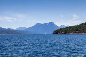 A sailboat o the Strait of Georgia with mountains behind, BC Canada