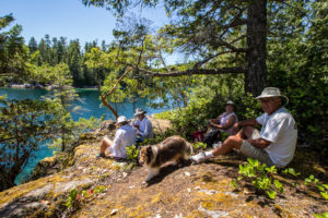 People and a dog picnicking on a bluff in Prideaux Haven, Desolation Sound, BC Canada