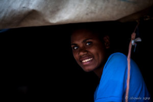 Motu woman smiling from a dark window, Hanuabada Village, Papua New Guinea