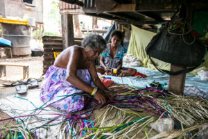 Old woman weaving under a stilted house, Hanuabada Village, Papua New Guinea