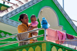 Nepali Mother and Baby on the balcony of a green house, Panauti-Namobuddha Rd, Nepal