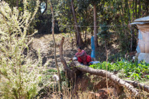 A woman doing dishes in her back yard, Panauti-Namobuddha Rd, Nepal