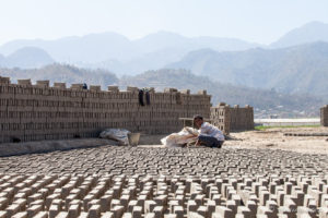 Nepali man laying out bricks for sun-drying, Panauti-Namobuddha Rd, Nepal