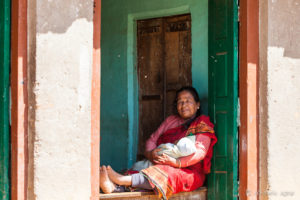 Grandmother seated in a large window with a baby, Panauti-Namobuddha Rd, Nepal