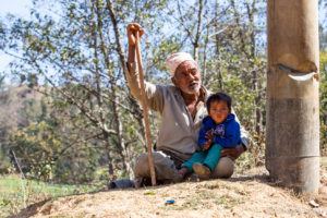 Old Nepali man with a young child, Panauti-Namobuddha Rd, Nepal