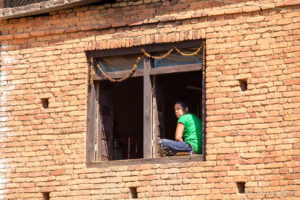 Woman sitting in an upper-story Window, Panauti-Namobuddha Rd, Nepal