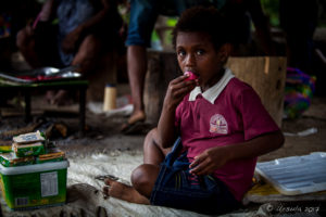 Papuan girl eating sweets in a market, Maprik PNG