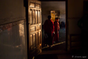 Two young monks going into a dark kitchen, Thrangu Tashi Yangtse Monastery, Namo Buddha Nepal