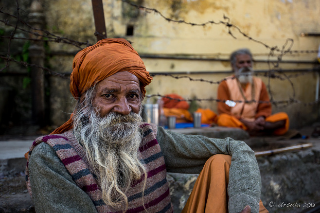Sadhus sitting against a yellow wall, Rishikesh, India