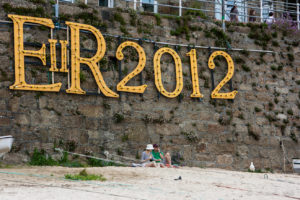 Two people sitting on a beach, Mousehole Cornwall UK