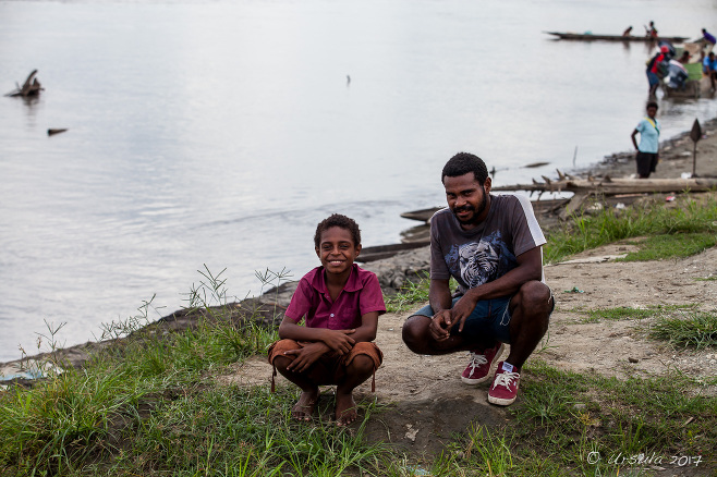 Papuan man and boy crouching on the bank of the Sepik River, Pagwi, PNG