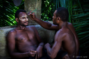 Crocodile man applying face paint to another, Kanganaman Village, PNG