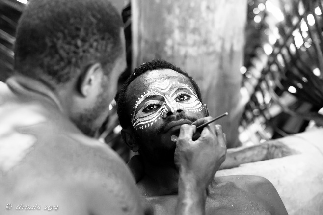 B&W portrait of a crocodile man being face-painted with cassowary eyes, Middle Sepik, PNG