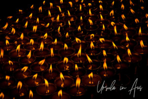 Flames of many Buddhist prayer lamps in the dark, Boudhanath Stupa, Kathmandu.