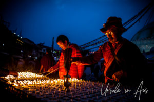 Tibetan Buddhist man lighting candles at Boudhanath Stupa, Kathmandu.