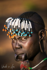 Mursi woman with beaded hair and a loose lip, Ethiopia