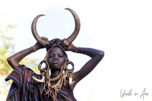 Youngster with Cow Horns against a white sky, Omo Valley Ethiopia