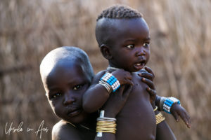 A Mursi toddler hold a younger baby, Omo Valley Ethiopia
